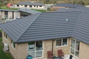 Grey concrete roofing product used on a small modern home with beige brick